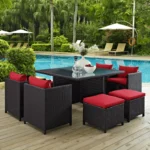 7 piece dark brown wicker outdoor dining set with red cushions, ottoman, and table without glass top.”