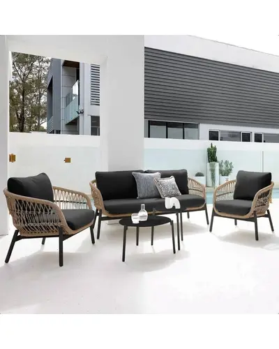 Outdoor garden 4 seater rope sofa in beige cushions and black frame placed on a patio with greenery.