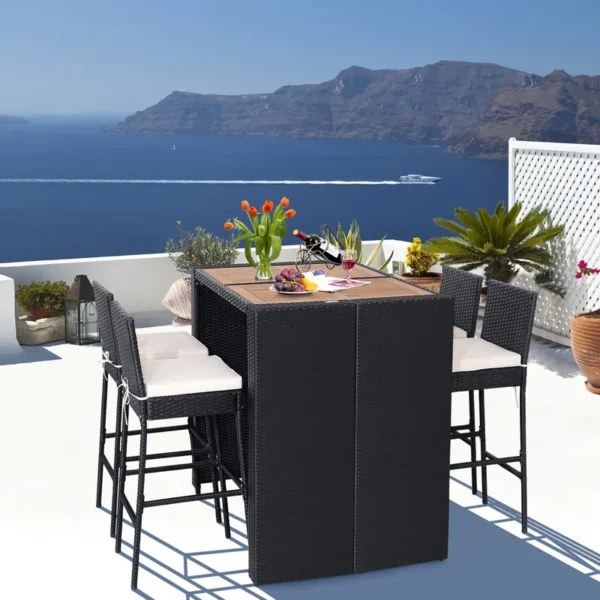 5 piece outdoor patio rattan bar set in black and white with high chairs and a bar table arranged on a garden patio.