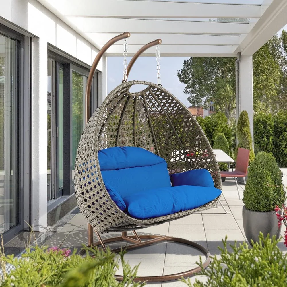 Double seater hanging swing chair in dark brown and blue, made of sturdy rattan with soft cushions, perfect for outdoor relaxation.