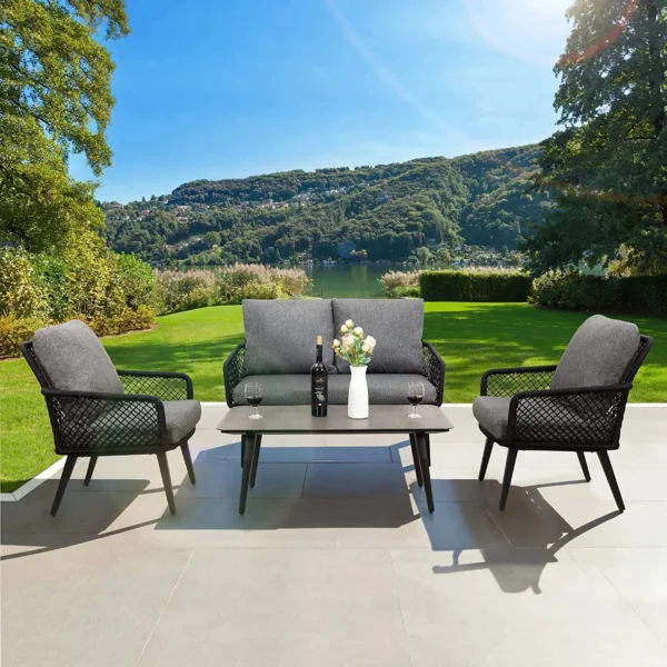 4-seater outdoor/indoor black and grey sofa set with center table and cushioned chairs, placed on a patio.