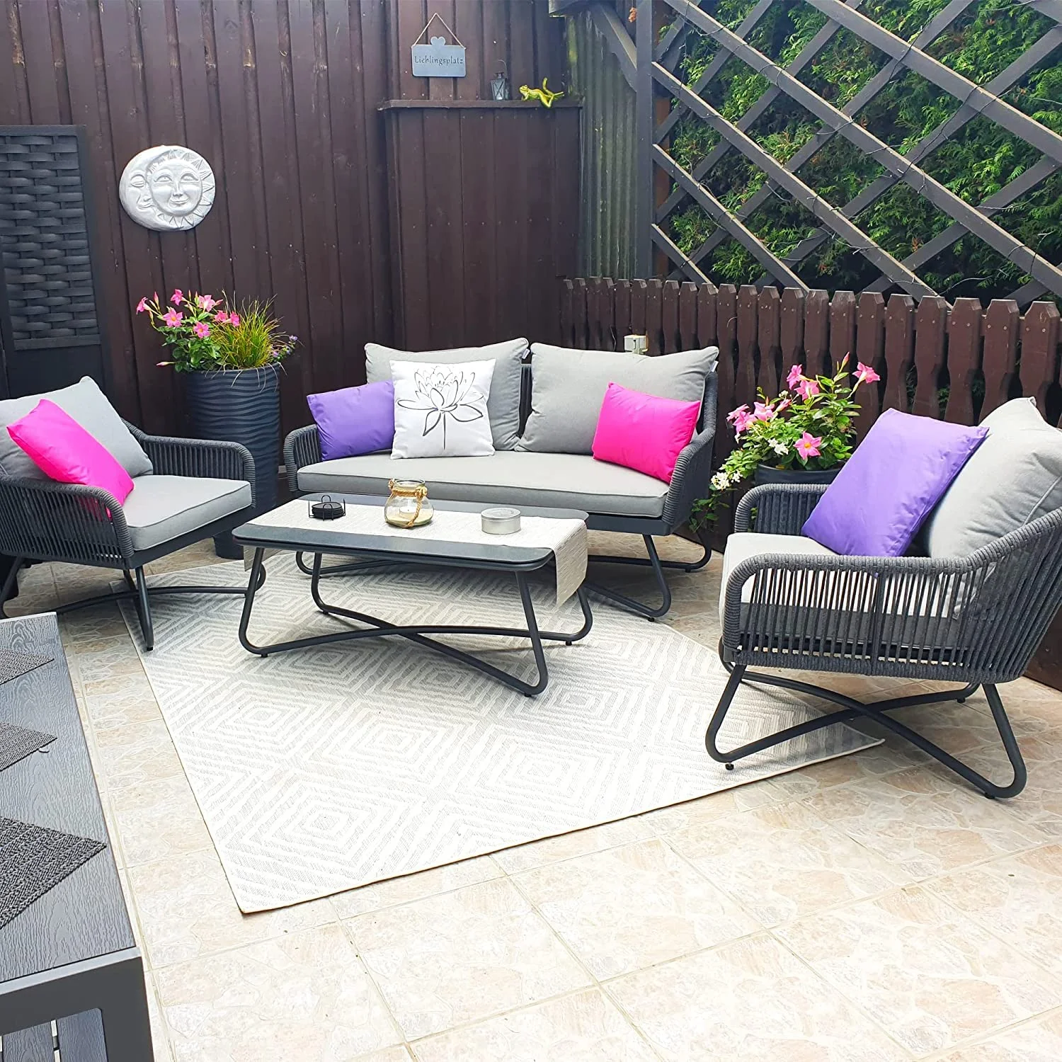 Grey 4-seater outdoor sofa set with plush cushions and matching table on a patio.