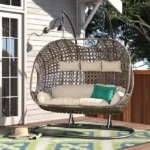 Three-seater hanging swing with sturdy stand in dark brown frame and cream cushions, perfect for balcony or garden relaxation.