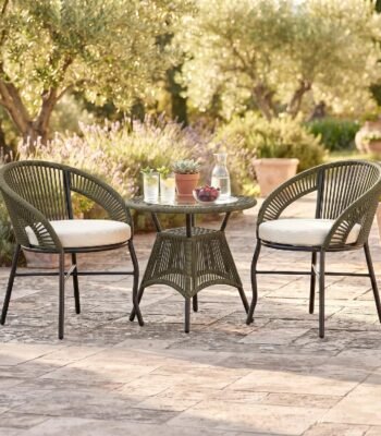 Loccus 2 Seater Outdoor Patio Furniture Set with two handwoven rope chairs, cream cushions and round glass-top table in a garden setting.